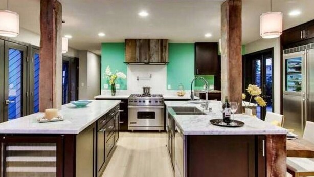 A modern kitchen with a central island, stainless steel appliances, and a green accent wall. - Surfrider at the Del Mar Beach Colony (Del Mar)