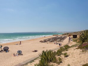 A beach with sun loungers, umbrellas, and a wooden boardwalk. - Stunning private villa for 11 guests with A/C, private pool, WIFI, TV and terrace (Galé)