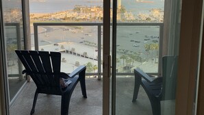 A balcony with two chairs, a view of a marina, and a distant cityscape. - Ocean Blvd (Long Beach)