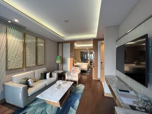 Une chambre d’hôtel moderne équipée d’un canapé, d’une table basse, d’une télévision et d’un coin repas avec une table et des chaises.