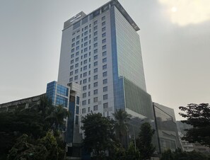 Un grand hôtel à la façade moderne en verre, avec de nombreux étages et une enseigne bien visible au sommet.