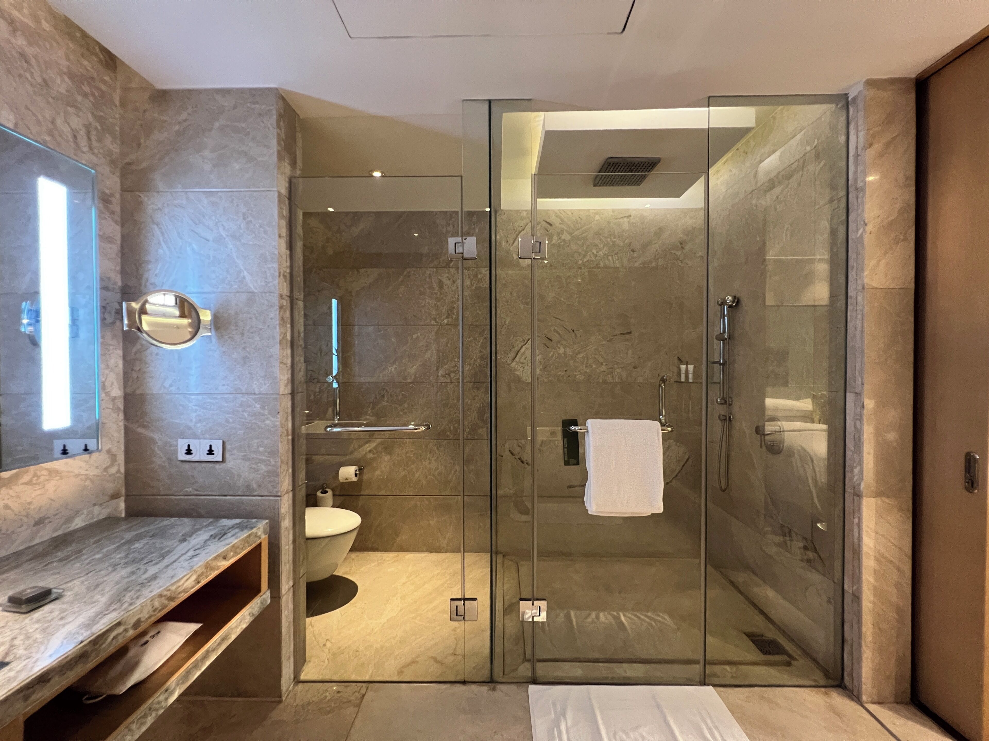 Un baño moderno con ducha acristalada, tocador de mármol y retrete.