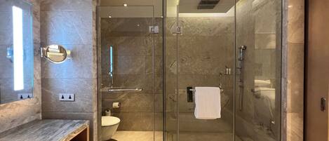 Un baño moderno con ducha acristalada, tocador de mármol y retrete.