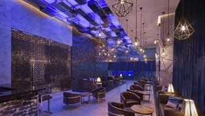 Ein moderner Lounge-Bereich mit Ledersofas, Tischen und hängenden geometrischen Leuchten.