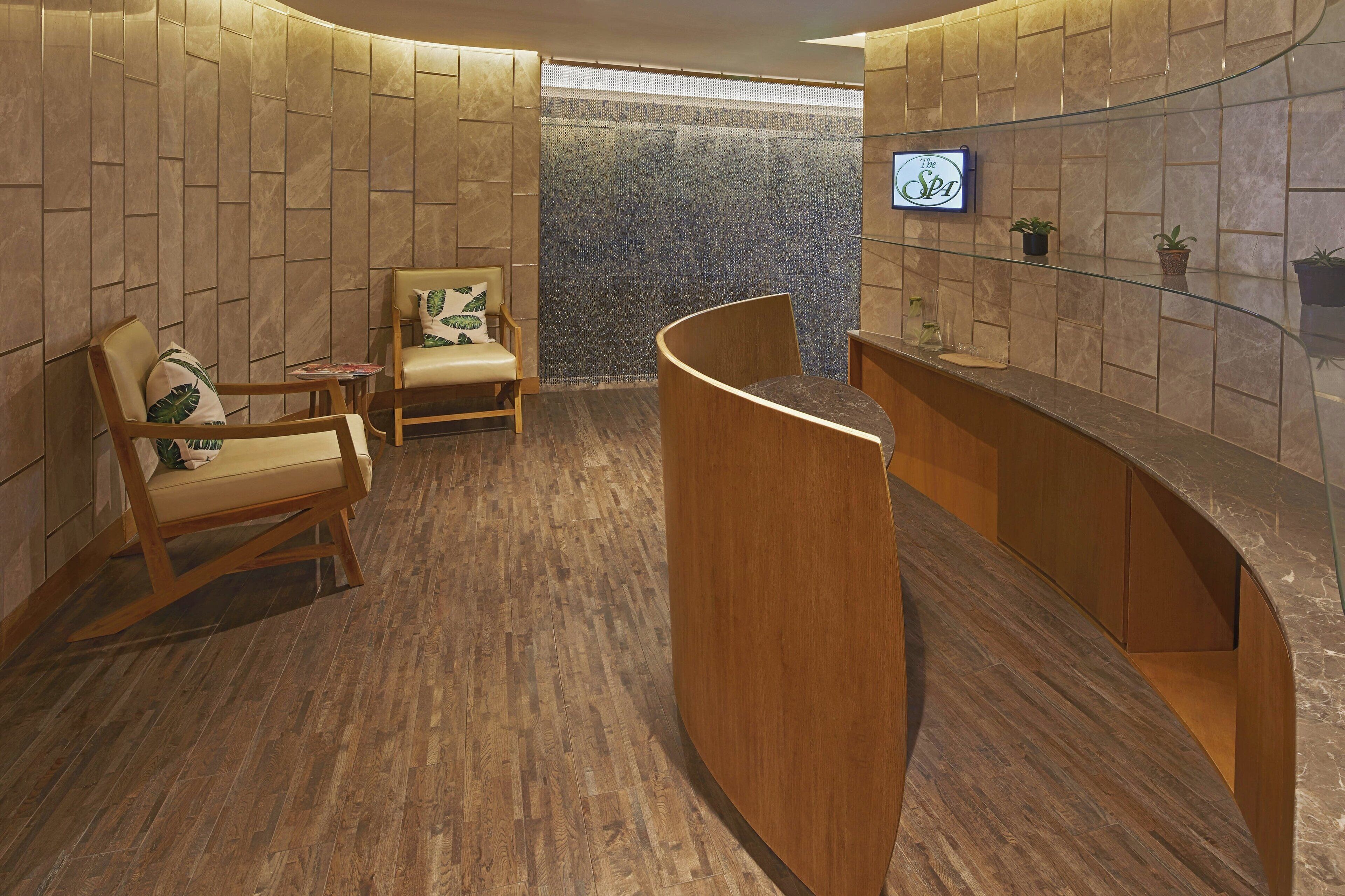 A reception area with wooden furniture, a reception desk, and a wall with a textured pattern.