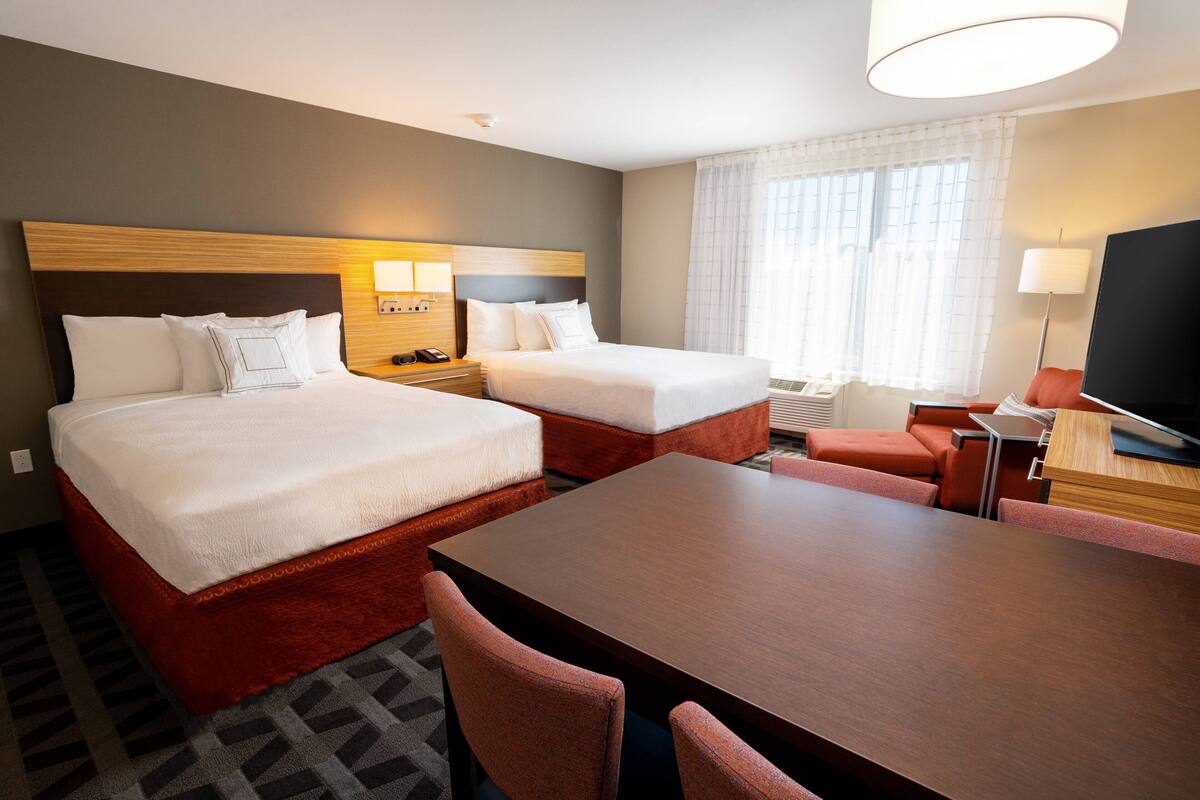 Een hotelkamer met twee bedden, een eettafel en een televisie.