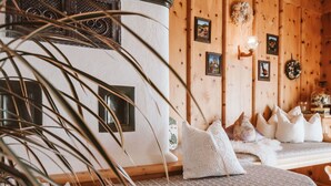 Una habitación acogedora con un muro de madera, un sofá estampado y un adorno colgante.