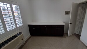 Ein Zimmer mit einer weißen Arbeitsplatte, dunklen Schränken, einer Heizung und einer Tür.