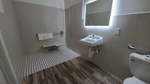 A modern bathroom with a shower, sink, toilet, and a small bench.