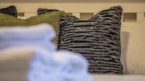 Un gros plan d’un lit avec un oreiller gris texturé et un oreiller vert.