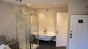 Une salle de bain moderne avec une douche à parois de verre, une baignoire sur pieds et une porte blanche dotée d’une poignée noire.