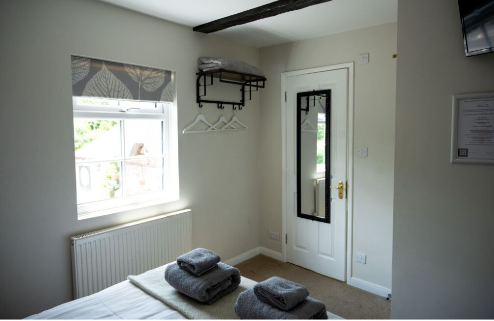 Une chambre avec un lit, une fenêtre donnant sur un beau paysage, une porte avec un miroir et un porte-serviettes.