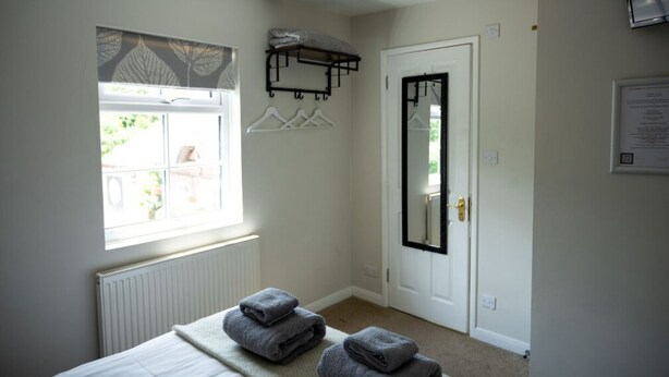 Un dormitorio con cama, ventana con vistas, puerta con espejo y perchero para toallas.
