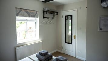 Une chambre avec un lit, une fenêtre donnant sur un beau paysage, une porte avec un miroir et un porte-serviettes.
