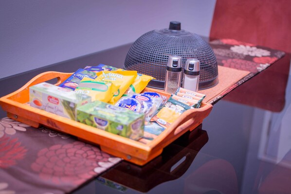 A tray with various snack items and two salt shakers on a table with a decorative item in the background.