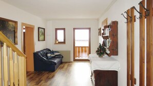 Una sala de estar con una escalera de madera, un sofá de cuero negro, un mueble de madera y un pequeño árbol de Navidad.