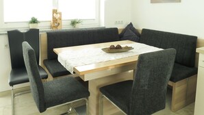 A modern dining area with a wooden table, grey upholstered chairs, and a bench. - Beautiful apartment for 4 people with WIFI, TV and terrace (Ramsau Im Zillertal)