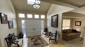 A spacious living area with hardwood flooring, a large window, a chandelier, and a beige sofa. - A Spacious Home With Great Views & Wildlife (Parker)