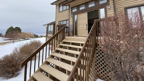 A two-story building with a wooden staircase leading to a deck. - A Spacious Home With Great Views & Wildlife (Parker)