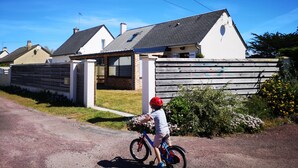 A residential area with houses, a child on a bicycle, and a clear blue sky.