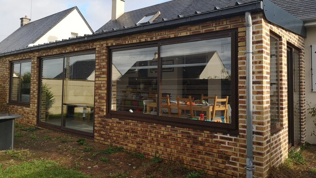 A brick house with large windows and a tiled roof.