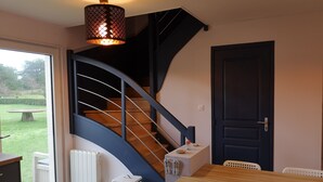 A modern interior with a curved staircase, a dining area, and a view of the outdoors.