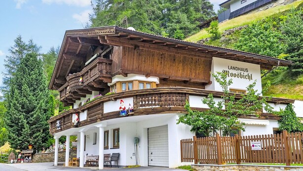 Ein traditionelles Holzhaus mit einem Schild, auf dem 'Landhaus Rösbichl' steht.