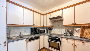 Eine kompakte Küche mit weißen Schränken, einer Mikrowelle, einer Kaffeemaschine und einem Toaster.