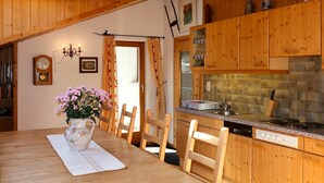 A cozy wooden dining area with a table set for four, a vase of flowers, and a wooden ceiling. - Nice apartment for 8 people with WIFI, TV and balcony (Prutz)