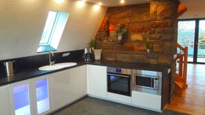 A modern kitchen with a stone accent wall, built-in appliances, and a skylight.
