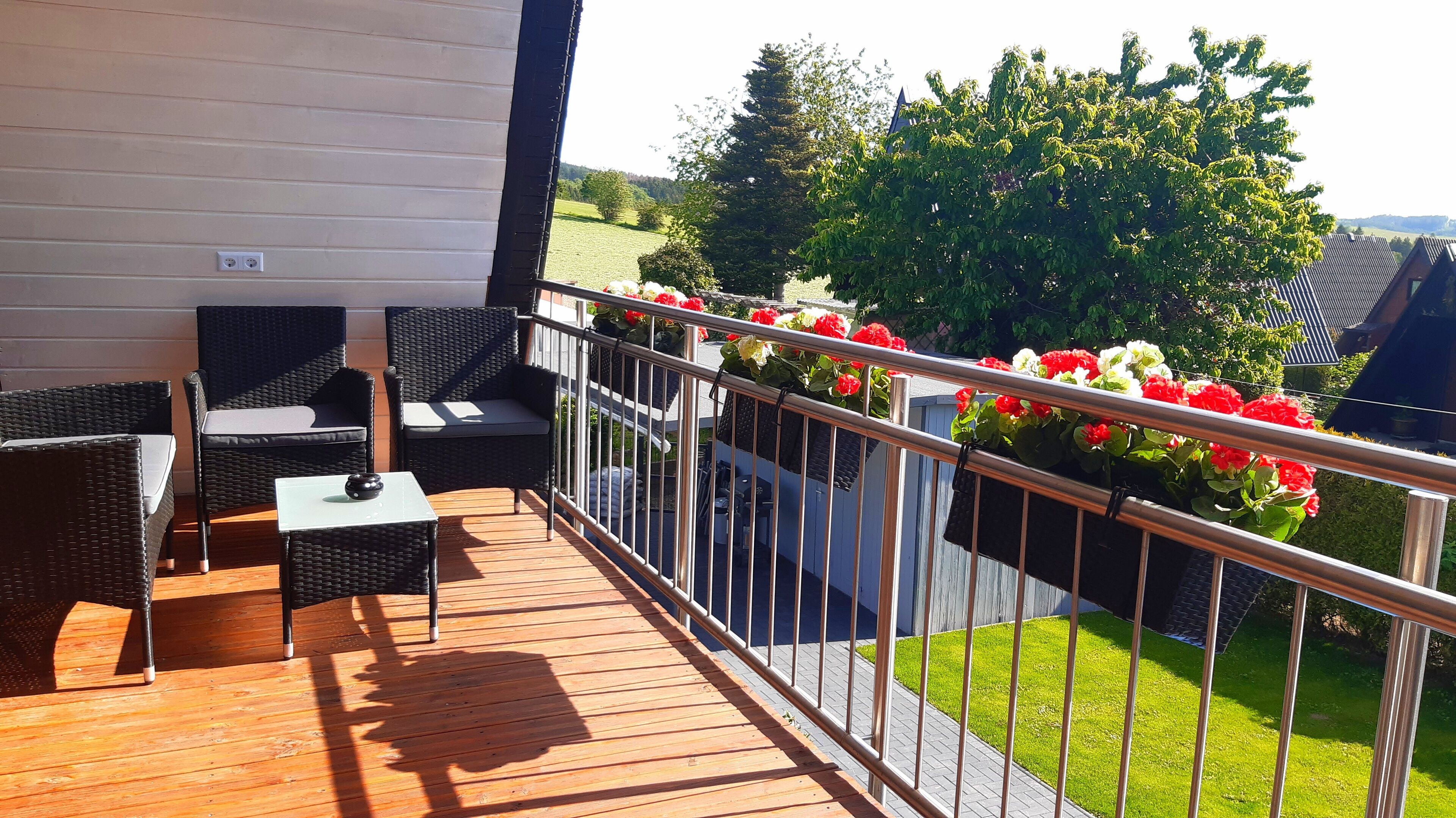 A wooden deck with wicker furniture and a small table.