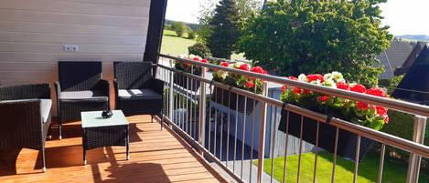 A wooden deck with wicker furniture and a small table.
