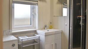 Een badkamer met een raam, een wastafel, een spiegel en een douche.