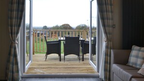 Een kamer met een schuifdeur die leidt naar een terras buiten, met rieten meubels.