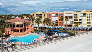 Un hotel con piscina, varios balcones y palmeras.