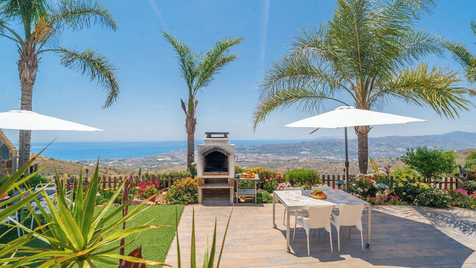 Un patio con una parrilla, mobiliario exterior y vista al mar.