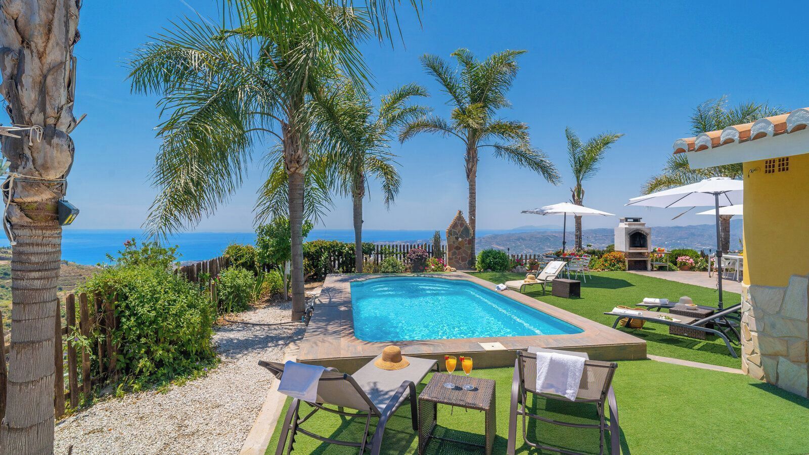 Una piscina con lettini, un'area barbecue e vista mare.