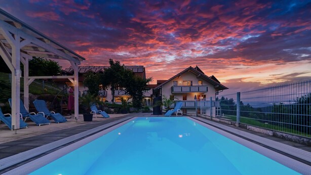 A swimming pool with lounge chairs, a covered area, and a house with a balcony. - Stunning private villa for 17 guests with pool, WIFI, TV, terrace and pets allowed (Baierweg)