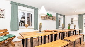 A dining area with wooden tables and benches, green curtains, and a white ceiling fan. - Stunning private villa for 17 guests with pool, WIFI, TV, terrace and pets allowed (Baierweg)