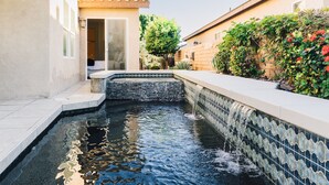 A swimming pool with a tiled edge, a stone-lined interior, and a small waterfall feature. - Golf Course Luxury with Pool, Spa, Casita & Mountain Views! (Indio)