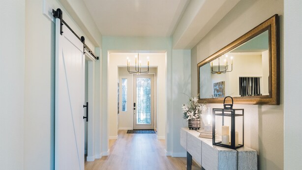 A hallway with a sliding door, a console table with a mirror, and a chandelier. - Golf Course Luxury with Pool, Spa, Casita & Mountain Views! (Indio)