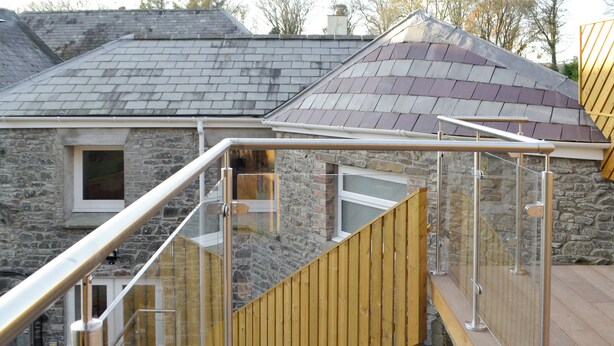 A wooden staircase with glass railings leading to a stone building with a sloped roof. - Cornel Clyd (Cosy Corner) (Felinfach, near Lampeter)