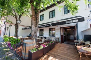 Un restaurant amb terrassa, taules de fusta i jardineres plenes de flors.