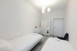 A small, clean room with two single beds, a desk, a chair, and a wardrobe. - Penzion La Route (Prague)