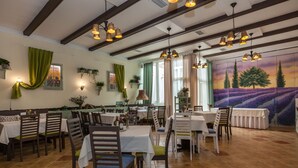 A restaurant with wooden tables and chairs, a mural of a lavender field, and hanging pendant lights. - Penzion La Route (Prague)