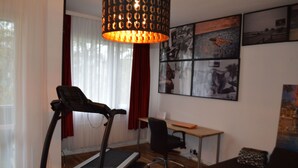 Quarto com esteira, escrivaninha e sofá.