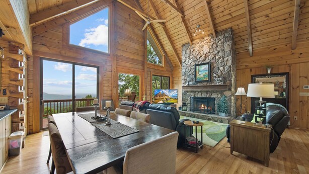 A spacious living area with a fireplace, a dining table, and a view of the outdoors. - 1 Sublime View - Beautiful views, hot tub, great amenities, close to Boone! (Deep Gap)