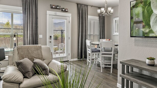 A modern living room with a sofa, dining area, and a TV mounted on the wall. - Serenity-Themed, Fastest WiFi, 2 King Beds Home (Medford)