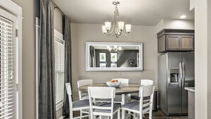 A dining area with a round table, white chairs, a chandelier, and a refrigerator. - Serenity-Themed, Fastest WiFi, 2 King Beds Home (Medford)