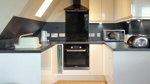 Una cocina moderna con horno empotrado, microondas y cafetera.